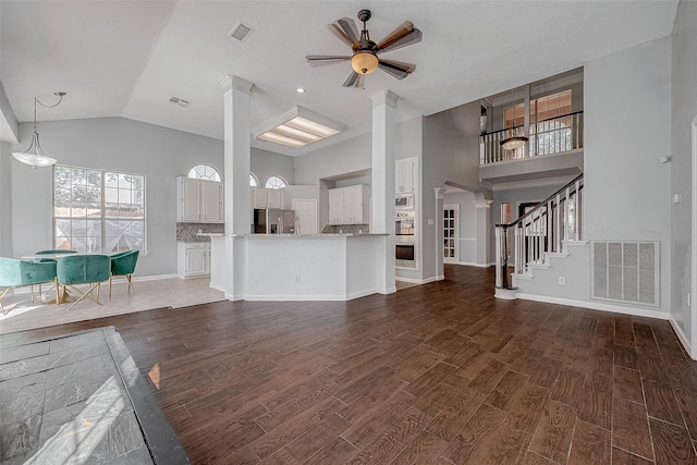 unfurnished living room featuring ornate columns, ceiling fan, dark wood-type flooring, and high vaulted ceiling