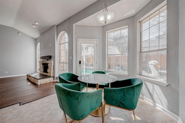 dining space with lofted ceiling, a fireplace, and light tile patterned floors