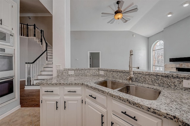 kitchen with light stone countertops, sink, and white cabinets