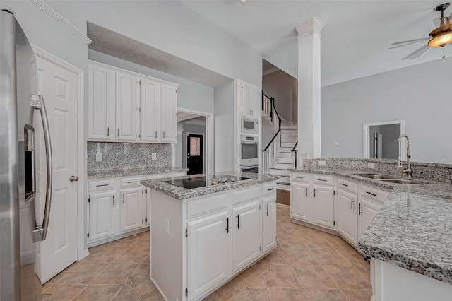 kitchen with sink, white cabinetry, a center island, black electric cooktop, and stainless steel fridge