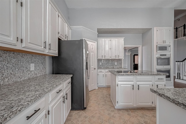 kitchen featuring stainless steel appliances, a center island, white cabinets, and light stone counters