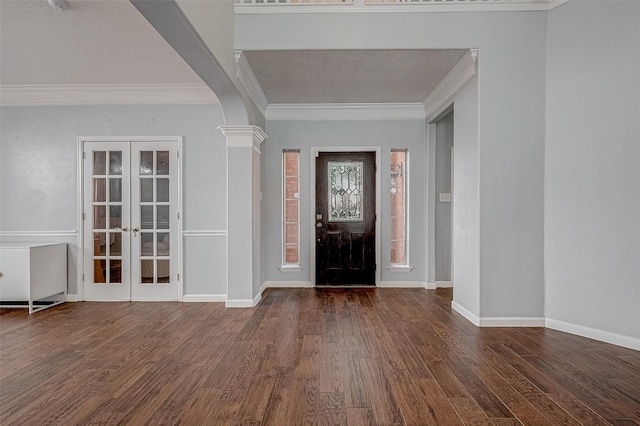 foyer with dark wood-type flooring, ornamental molding, french doors, and ornate columns