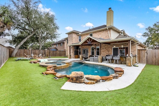 back of property with a yard, a patio area, and a pool with hot tub