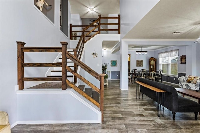 stairway with ornamental molding, a chandelier, a towering ceiling, and hardwood / wood-style floors