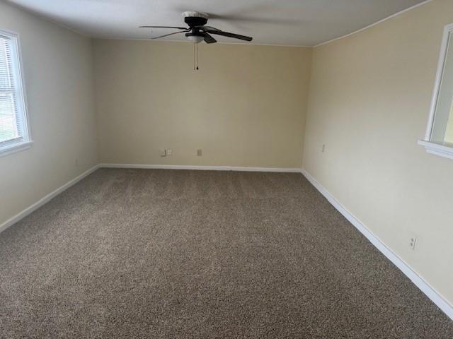 spare room with ceiling fan and dark colored carpet