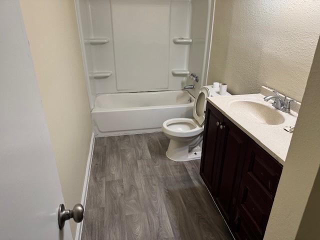 full bathroom featuring wood-type flooring, toilet, bathing tub / shower combination, and vanity