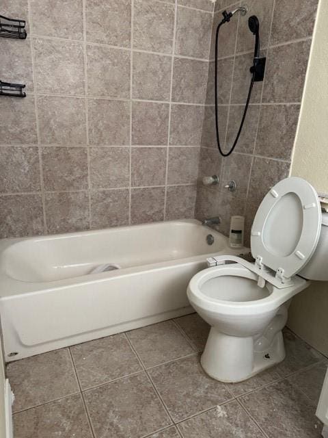 bathroom with tile patterned flooring, tiled shower / bath combo, and toilet