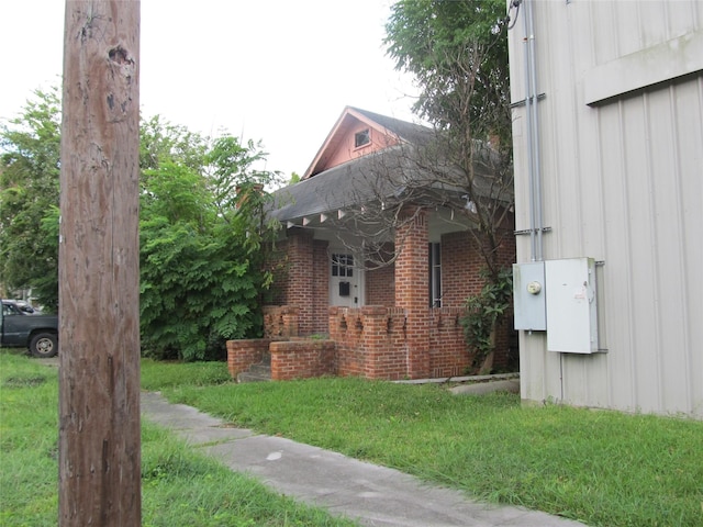 view of side of property with board and batten siding, a lawn, and brick siding