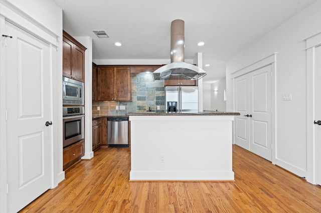 kitchen with tasteful backsplash, island range hood, a center island, light hardwood / wood-style flooring, and appliances with stainless steel finishes