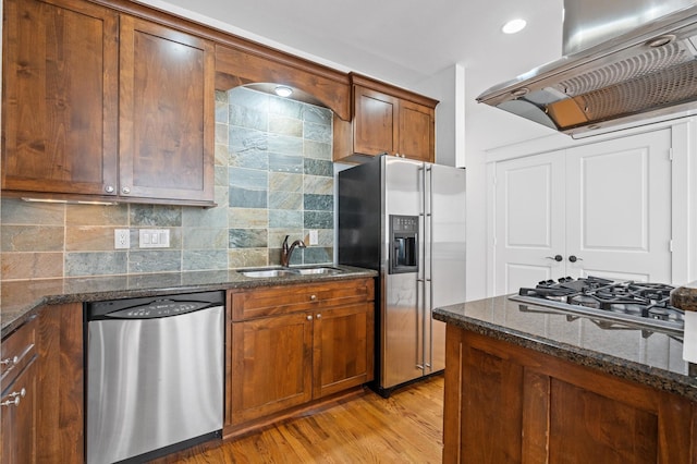 kitchen featuring sink, appliances with stainless steel finishes, dark stone countertops, island range hood, and decorative backsplash