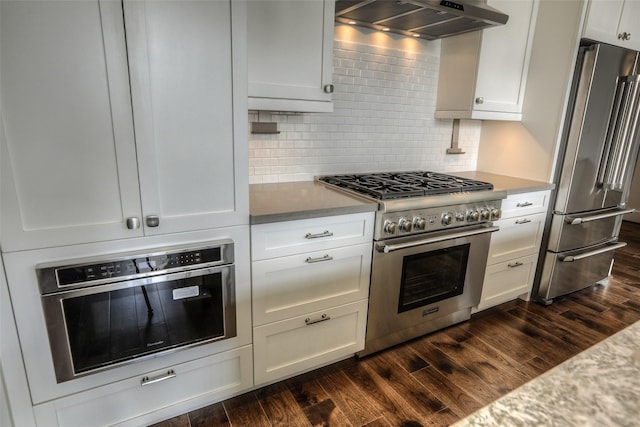 kitchen with white cabinetry, high end appliances, dark wood-type flooring, and extractor fan