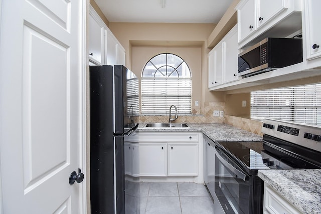 kitchen with stainless steel appliances, light stone countertops, sink, and white cabinets