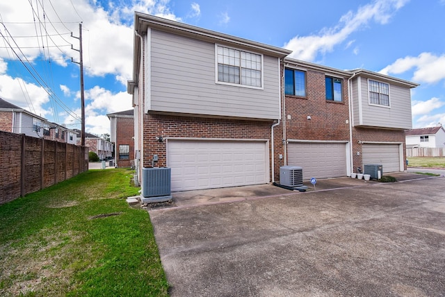 rear view of property featuring a garage, central AC, and a lawn