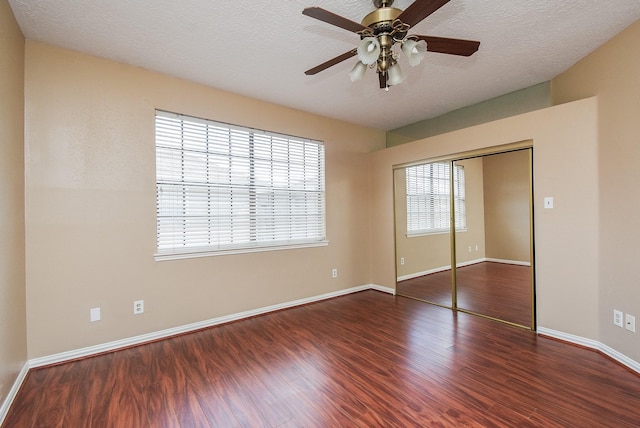 unfurnished bedroom with ceiling fan, dark wood-type flooring, a textured ceiling, and a closet