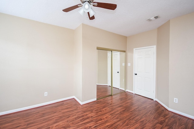 unfurnished bedroom featuring ceiling fan, dark wood-type flooring, a textured ceiling, and a closet