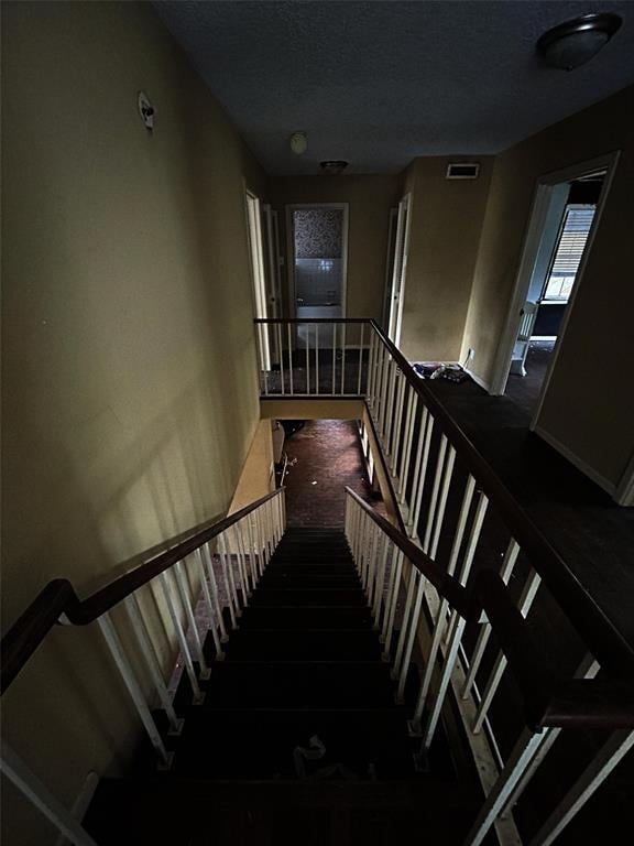 staircase with a textured ceiling