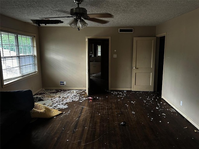 empty room with ceiling fan, dark hardwood / wood-style floors, and a textured ceiling