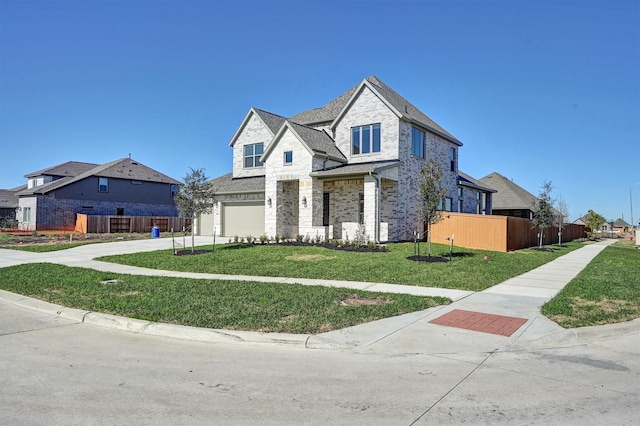 french country home featuring driveway, stone siding, fence, a front yard, and a garage