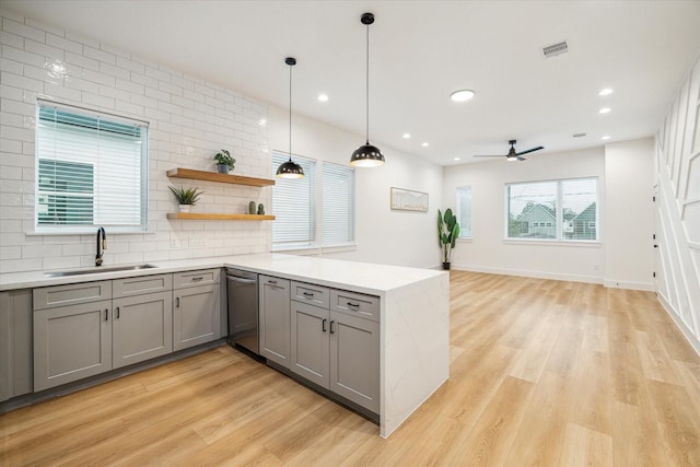 kitchen featuring gray cabinetry, a sink, light countertops, open shelves, and decorative light fixtures