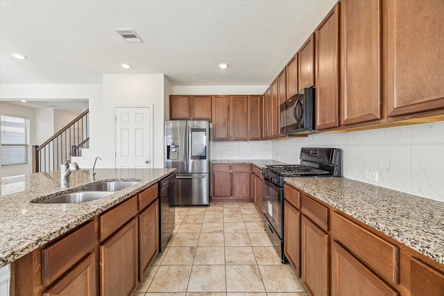 kitchen featuring light tile patterned flooring, sink, backsplash, black appliances, and light stone countertops