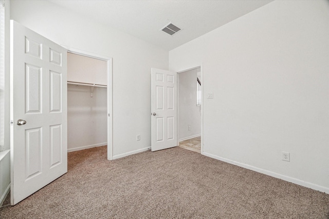 unfurnished bedroom with a closet, a spacious closet, and carpet