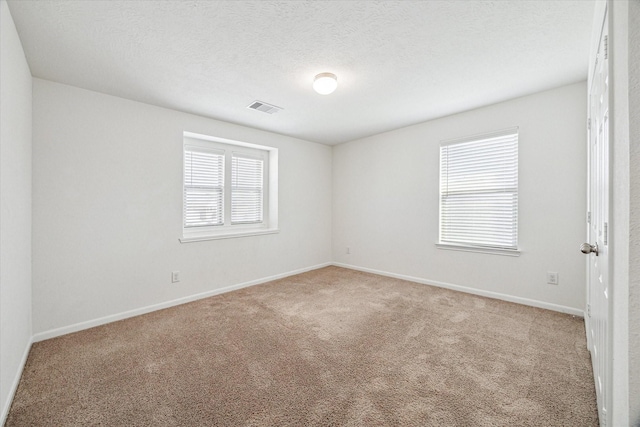 carpeted spare room with a textured ceiling