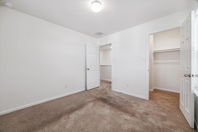 unfurnished bedroom featuring a walk in closet, carpet, and a closet