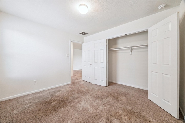 unfurnished bedroom with a closet, carpet, and a textured ceiling