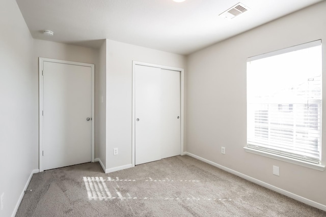 unfurnished bedroom featuring light carpet and a closet