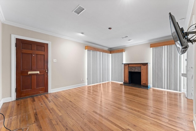 unfurnished living room with light wood-type flooring, a premium fireplace, visible vents, and crown molding