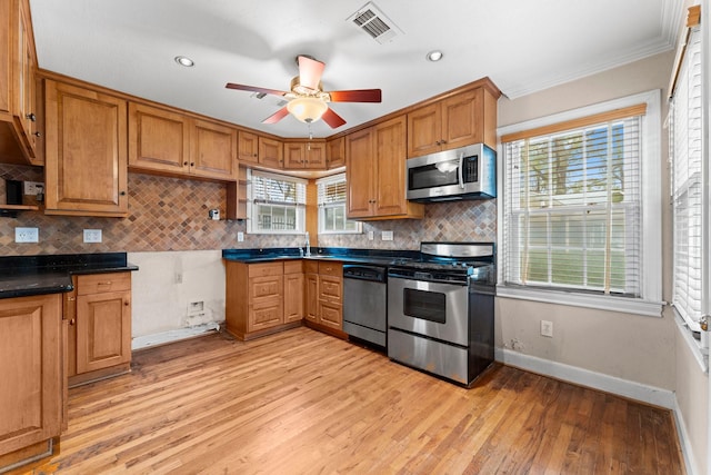 kitchen with visible vents, dark countertops, brown cabinets, stainless steel appliances, and light wood-type flooring