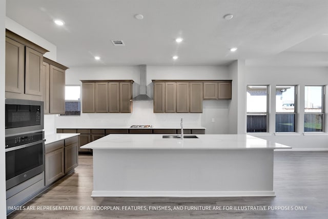 kitchen featuring visible vents, a wealth of natural light, stainless steel appliances, wall chimney exhaust hood, and a sink