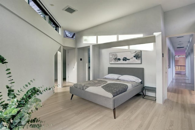 bedroom featuring light hardwood / wood-style flooring and high vaulted ceiling