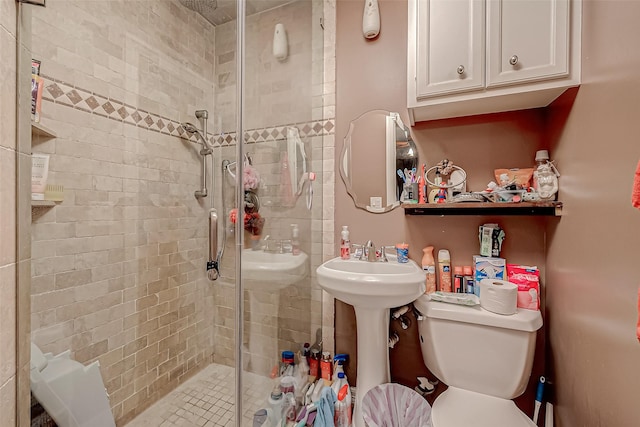 bathroom with a shower with door, sink, and toilet