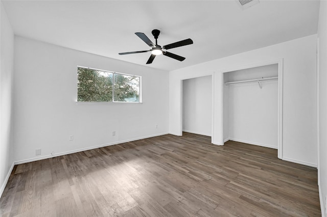 unfurnished bedroom with ceiling fan, visible vents, baseboards, and wood finished floors