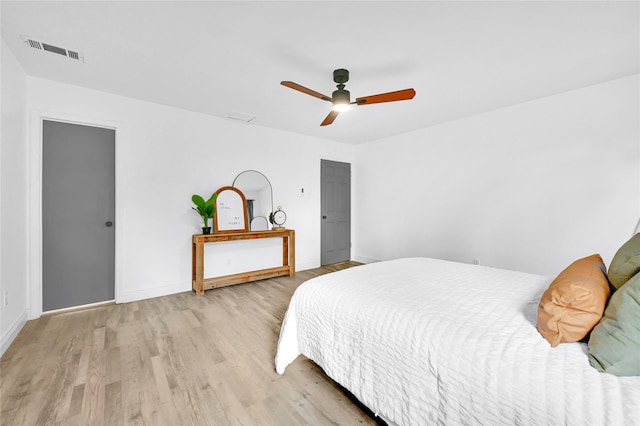 bedroom with a ceiling fan, wood finished floors, visible vents, and baseboards