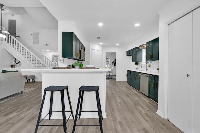 kitchen with light wood finished floors, green cabinets, dishwasher, and light countertops