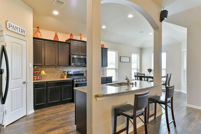 kitchen featuring sink, light stone counters, appliances with stainless steel finishes, dark hardwood / wood-style floors, and backsplash