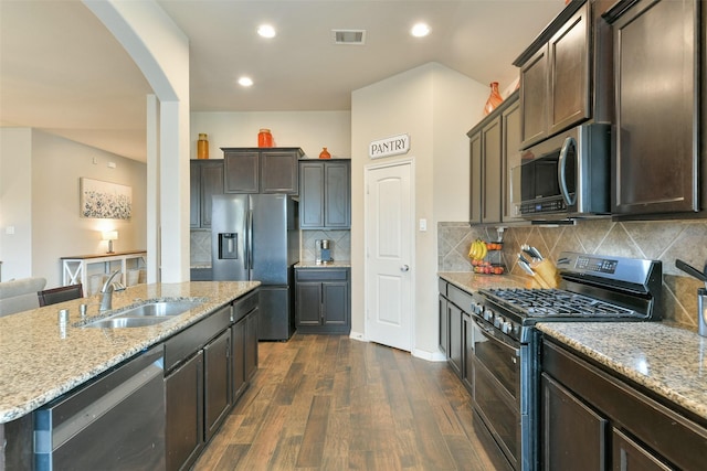 kitchen with sink, dark hardwood / wood-style flooring, a kitchen island with sink, stainless steel appliances, and light stone countertops