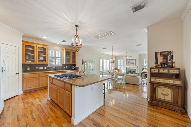 kitchen with a center island, decorative backsplash, stainless steel gas cooktop, and light wood-type flooring