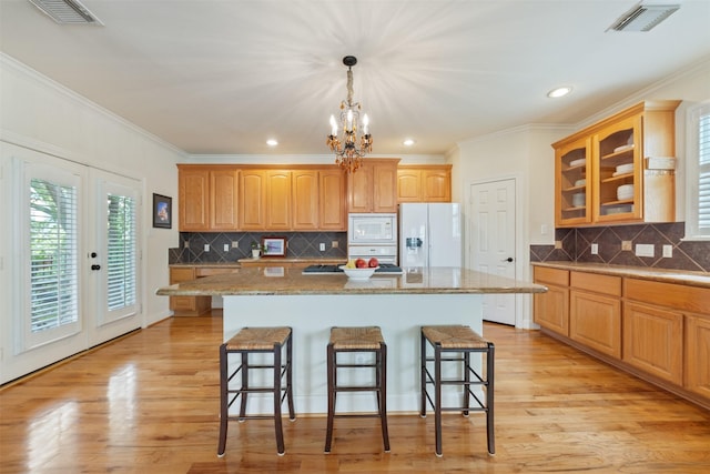 kitchen featuring pendant lighting, white appliances, a center island, and a kitchen bar