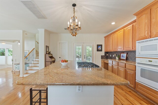 kitchen with hanging light fixtures, white appliances, french doors, and a kitchen island