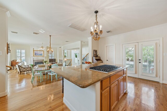 kitchen with stone counters, a kitchen island, a notable chandelier, and light hardwood / wood-style flooring