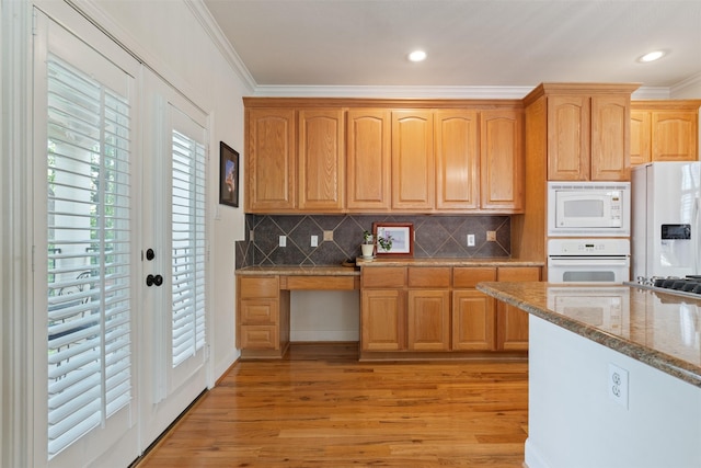 kitchen with crown molding, white appliances, light hardwood / wood-style floors, and light stone counters