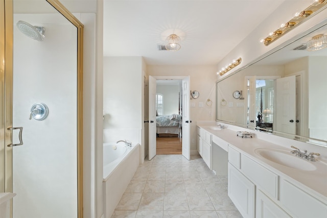 bathroom with a healthy amount of sunlight, vanity, tile patterned flooring, and tiled tub