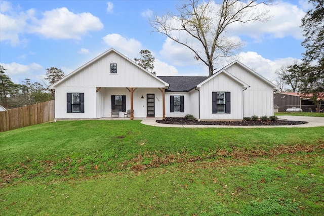 modern farmhouse style home with board and batten siding, fence, a shingled roof, and a front lawn