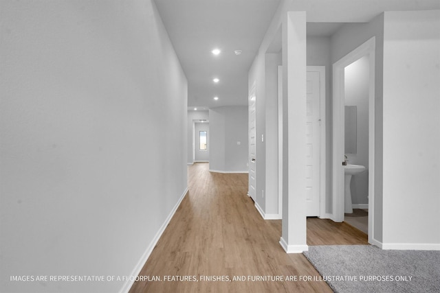 hall featuring recessed lighting, baseboards, and light wood-style flooring