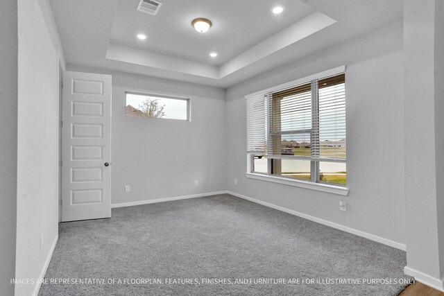 carpeted spare room featuring a tray ceiling, recessed lighting, baseboards, and visible vents