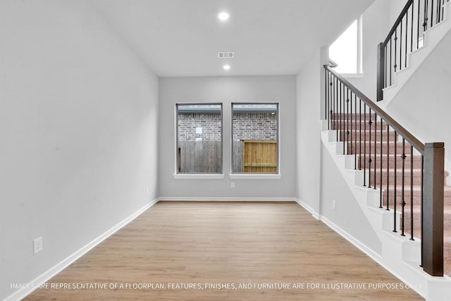 empty room with recessed lighting, stairway, baseboards, and wood finished floors