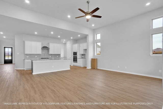 unfurnished living room with recessed lighting, baseboards, and light wood-style floors